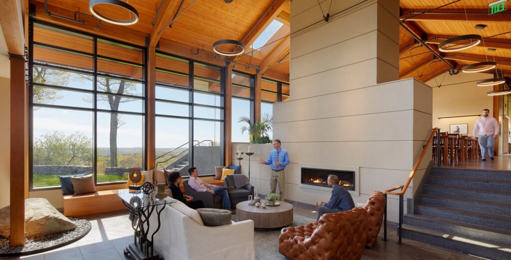 A modern living room, complete with warm lighting, a cozy fireplace, and wide windows showcasing the beautiful nature outside.