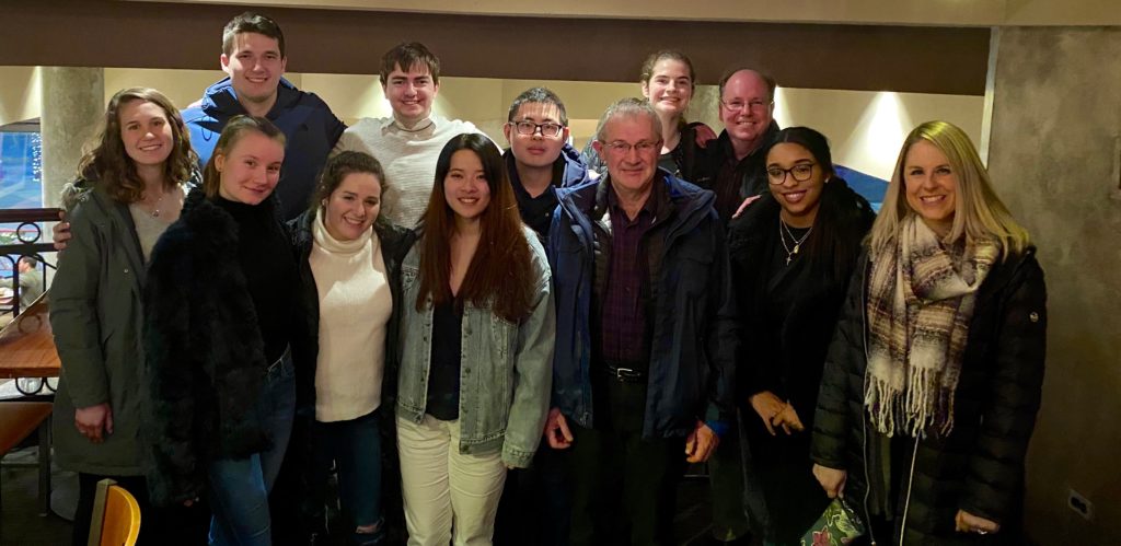 Students, alumni, and two faculty members posing during dinner at conference