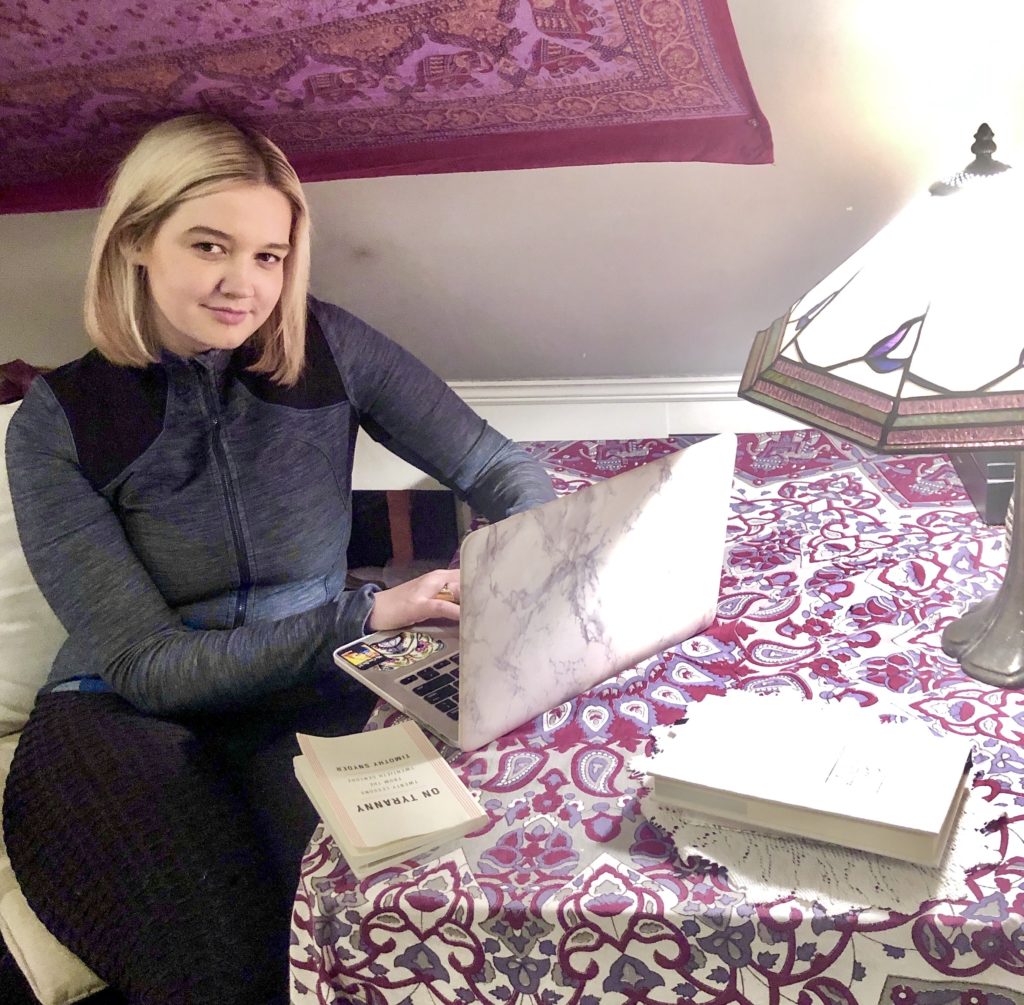 Emma Powell sitting at desk typing on laptop