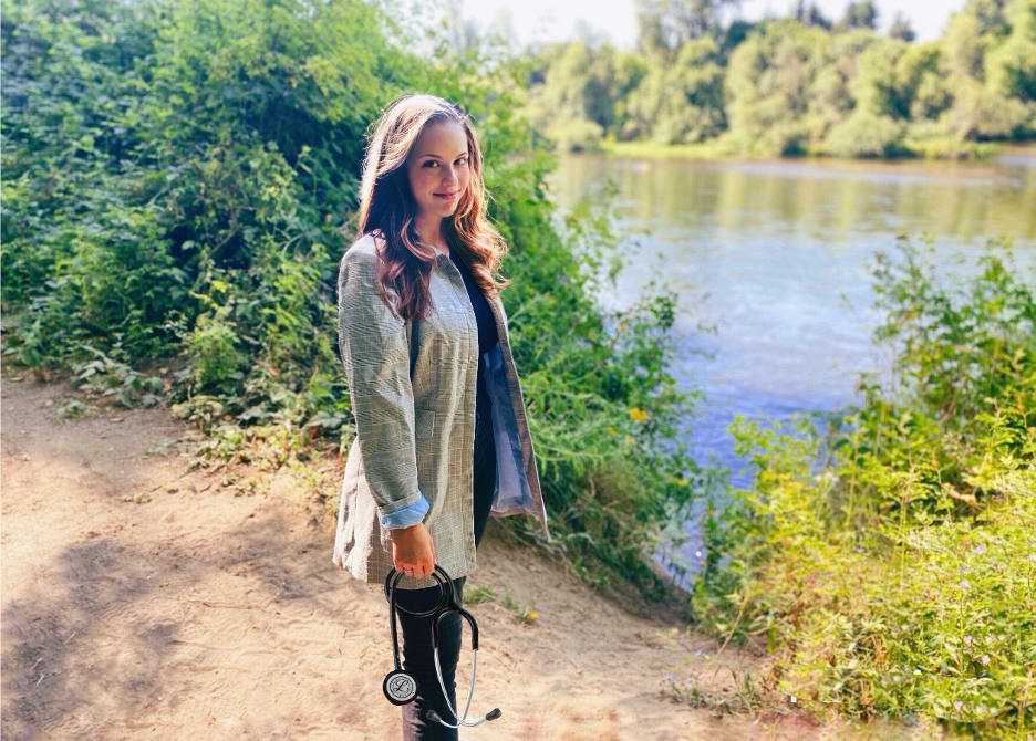 Young woman standing with stethoscope in front of river